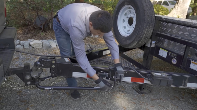 Man hooking up spring bar on weight-distribution hitch.