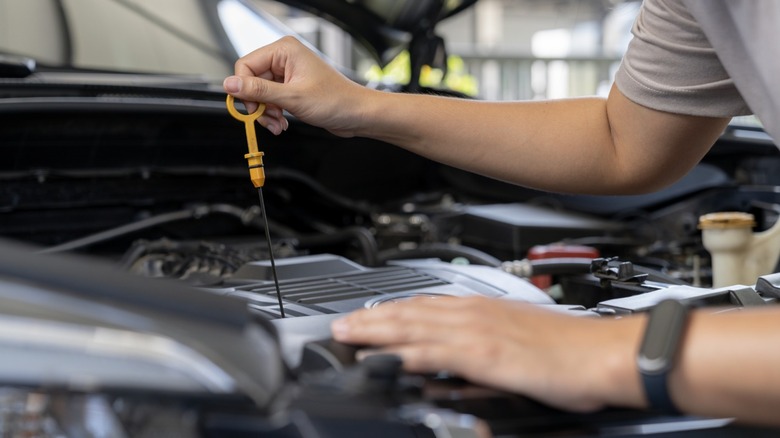 Man pulling the dipstick out to check the oil in his car.