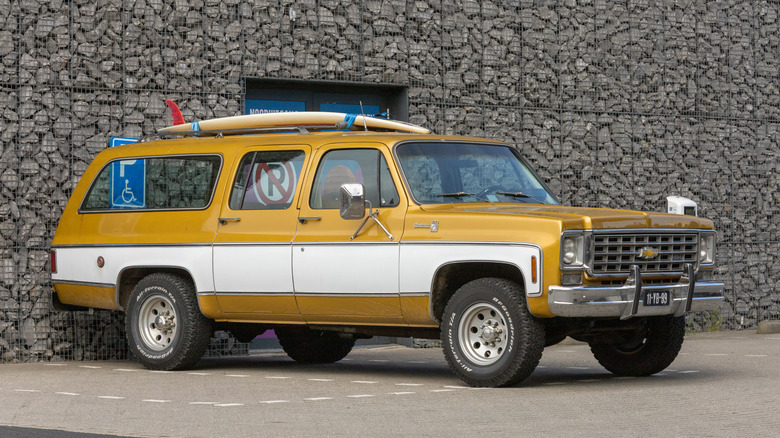 A vintage Chevrolet Suburban parked in a handicap spot