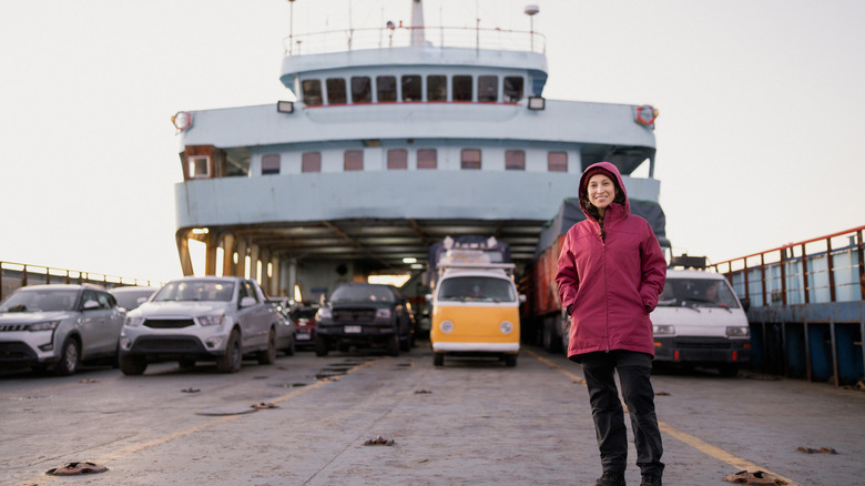 A woman stands in front of cars packed on a ferry.