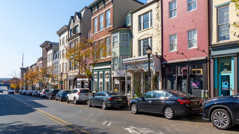 Cars are street parked in front of stores and townhomes.
