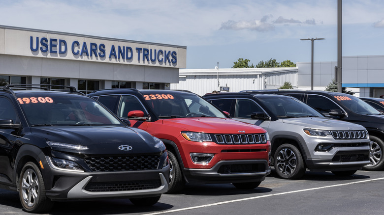 A line of used vehicles sits parked outside a used car dealership.