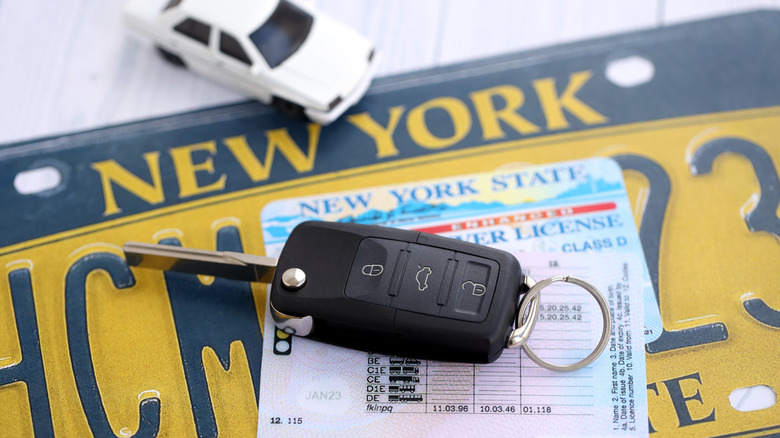 A car key sits on a New York State license plate.