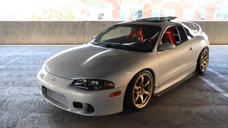A silver Honda Eclipse in a parking lot with hood bump