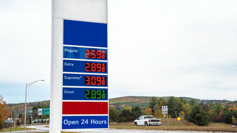Photo of a petrol station sign with prices along a highway on a cloudy autumn day. Countryside of Vermont, USA.