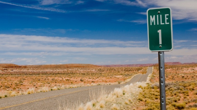 A green mile-1 mile parker posted on a desolate desert road.