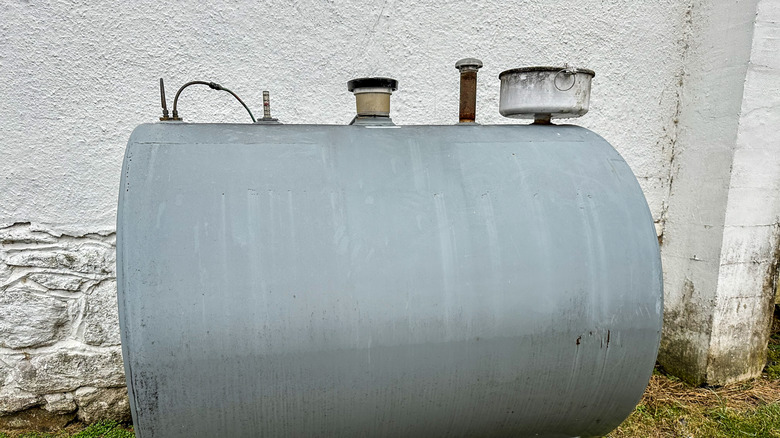 A heating-oil tank in a basement in front of a whitewashed wall.
