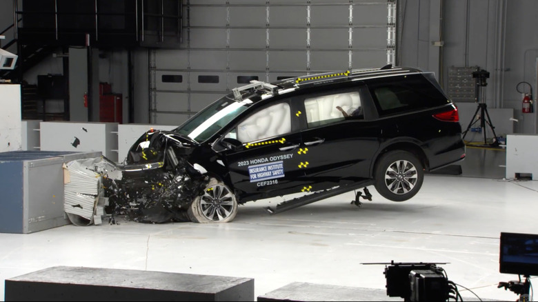 A screenshot from the IIHS moderate overlap front crash test showing a black Odyssey after it crashes in the IIHS lab