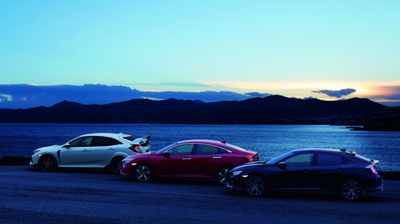 A 2017 Honda Civic Type R, sedan, and hatchback parked by the water at sunset