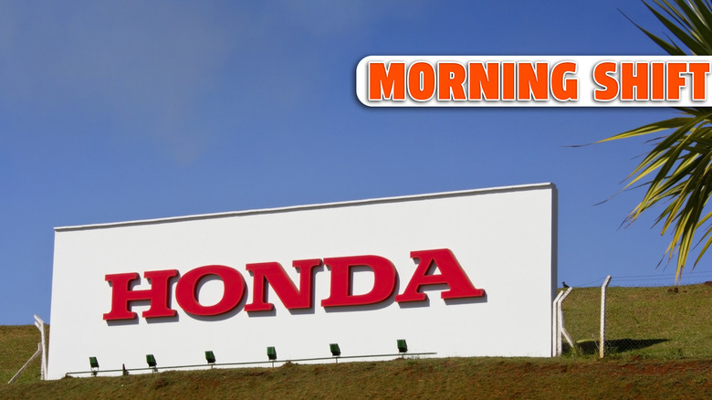 Photo of a wall, with the company name ""Honda"" written in red letter. Photo taken in front of the factory. Blue sky on background."