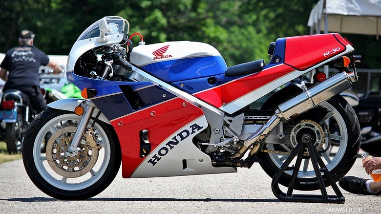 A red, white, and blue 1987 Honda RC30 in pristine condition, parked in the sun.