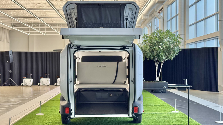A peek inside the Base Stationtrailer showing a white bench that says Honda in front of Motocompactos and a tree