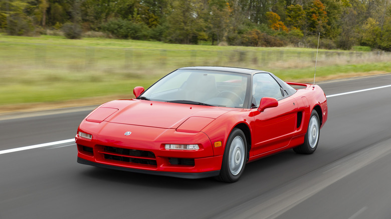 A red Acura NSX drives down a road