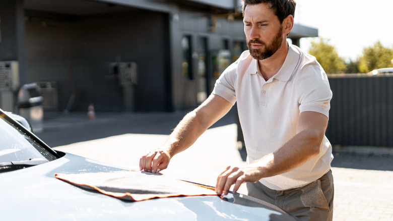 A man drying a car after washing using a microfiber mitt
