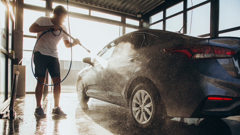 A man washing a car at a self-service car wash