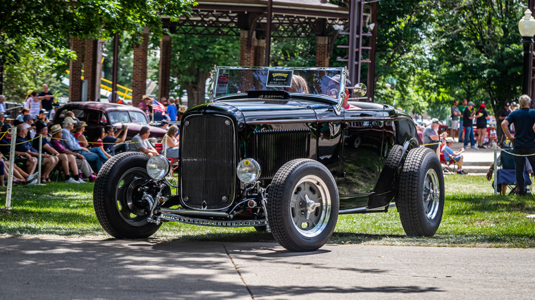 Black 1932 Ford highboy roadster hot rod seen in left front three-quarter view at an outdoor car show