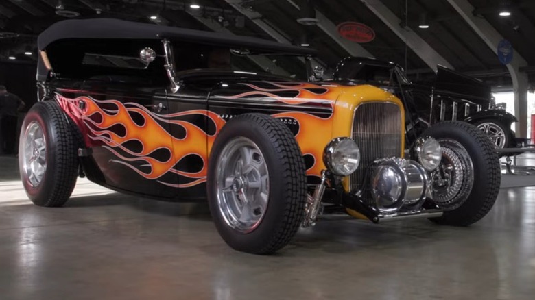 Beth Myers' 1932 Ford Phaeton Lowboy hot rod seen in right front three-quarter view, black with painted flames