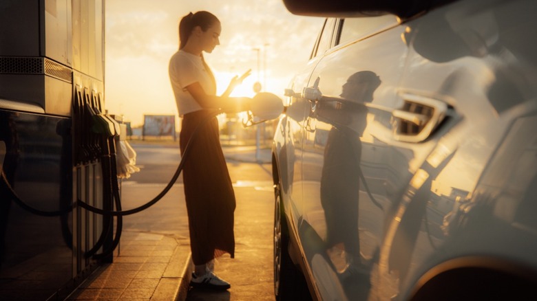 Woman pumping gas on sunny evening