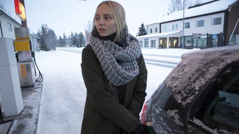 Woman pumping gas during winter