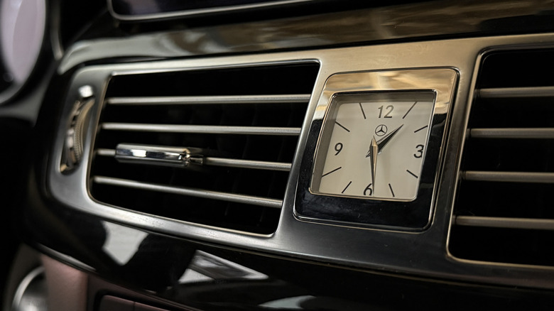 An analog clock on the dashboard of a 2016 Mercedes-Benz CLS 400, surrounded by the air vents and dark gloss-finished wood.