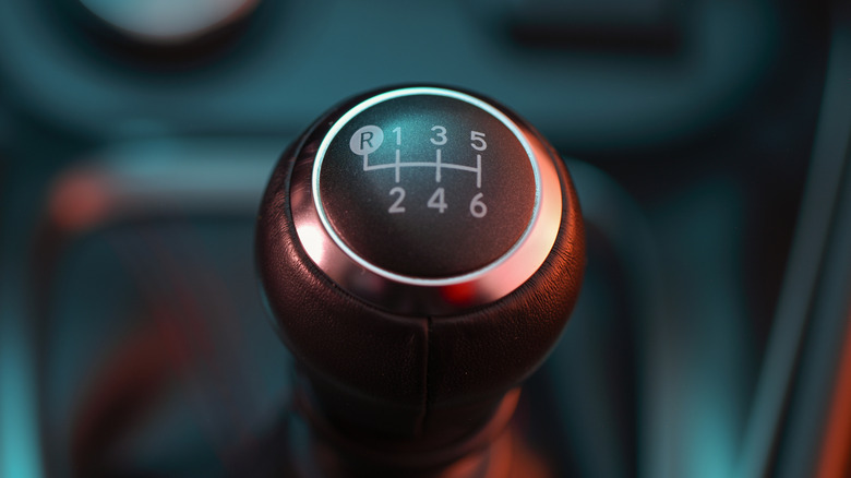 A black gear shift lever and knob in a 6-speed manual transmission car.