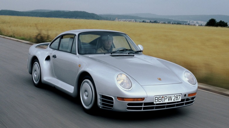 A front shot of a silver Porsche 959 on the road