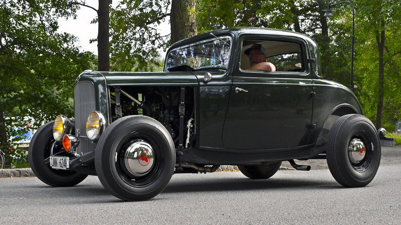 A 1932 Ford V8 coupe being driven on the road.