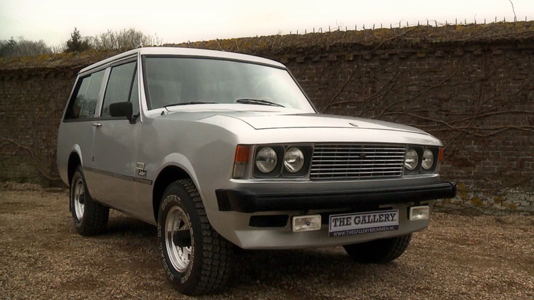 A silver Monteverdi Safari pared in front of a brick wall.