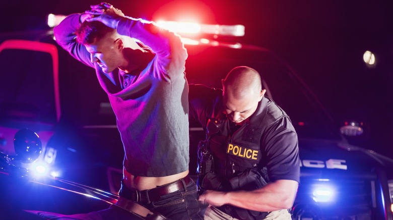 Officer searches a driver who has his hands locked over his head