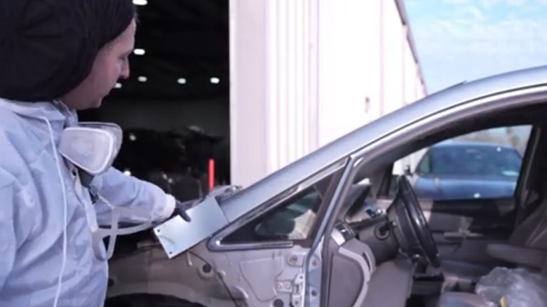 A man matches a swatch of paint to the car whose paint he will fix.