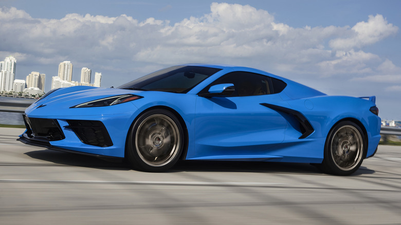 A blue 2024 Chevrolet Corvette Stingray parked with a city skyline in the background.