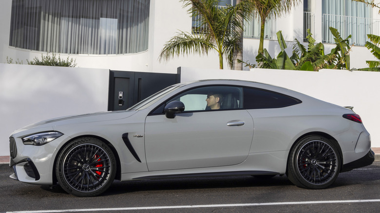 A 2024 Mercedes-AMG CLE 53 Coupe in Manufaktur Alpine Grey, parked in front of an apartment building