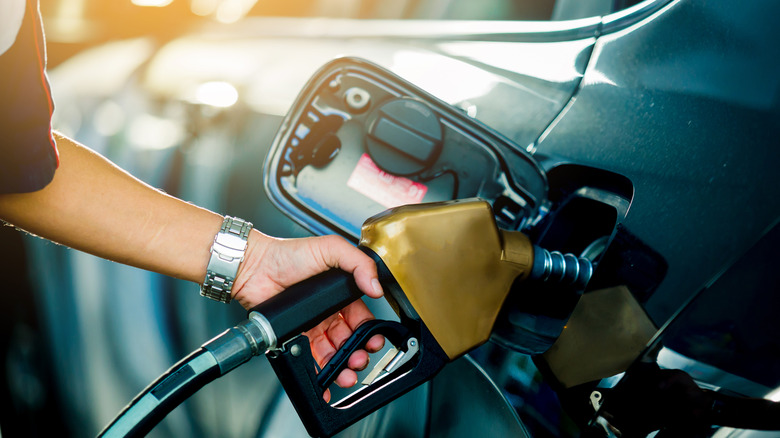 A person pumping gas with nozzle.