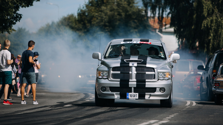 A silver Dodge Ram doing a burnout