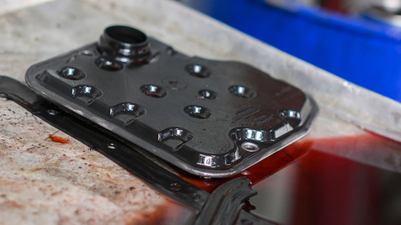 A used automatic transmission filter and ATF fluid in a garage pan