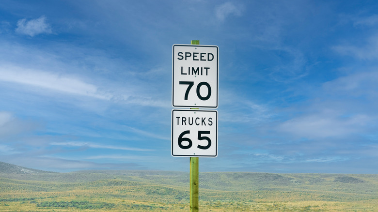 Black and white speed limit signs of 70 miles per hour and 65 miles per hour for trucks on a highway in the United States.