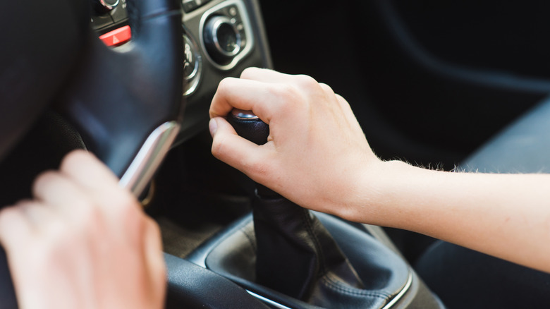 Driver holding the shifter of a manual car