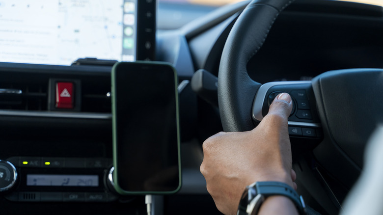 Driver pressing the cruise control button on the steering wheel