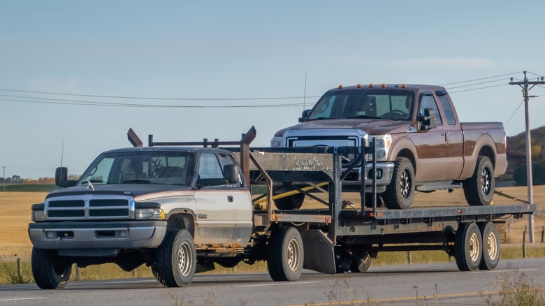 A 5.9L Cummins-powered Dodge Ram towing a Ford pickup on a trailer.