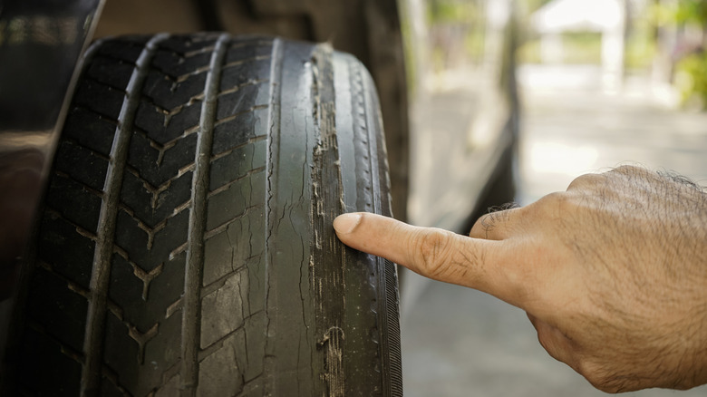 A person points towards a worn out car tire.