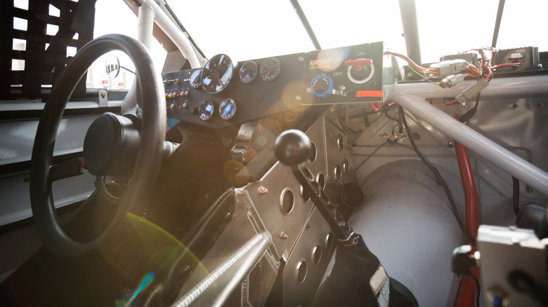 An interior of a manual race car with the sun beaming through the windshield.