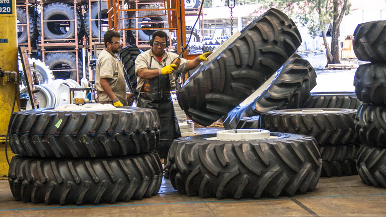 Workers at a factory mounting OTR tires to tractor wheels