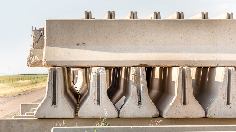 A stack of concrete highway barriers, which are shaped to help cars slide vertically up the wall face to reduce rollover risk.