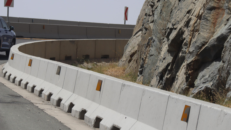 Concrete highway barriers along a winding mountain road.