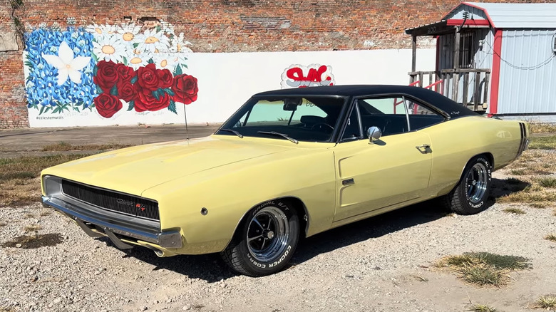A yellow 1968 Dodge Charger R/T 426 Hemi muscle car parked on gravel