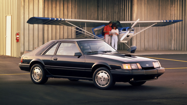 Ford Mustang SVO parked in front of a plane