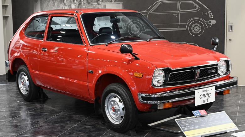 A red 1975 Honda Civic CVCC parked in a museum