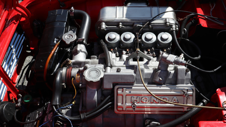 The 0.6-liter four-cylinder engine under the open hood of a red 1964 Honda S600 sports car