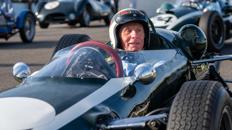 Jackie Stewart behind the wheel of a classic racecar