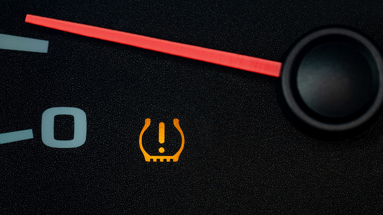An illuminated tire pressure warning light in the instrument console of a car.